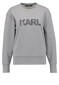 Sweat-shirt gris à manches longues avec col rond, poignets et ourlet côtelés, avec « KARL » imprimé en grandes lettres foncées sur la poitrine.