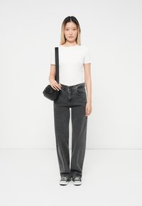 Sorte høyde på midjen jeans med brede ben, kombinert med en tettsittende hvit kortermet topp og en liten svart crossover-veske. Klassiske joggesko fullfører antrekket.