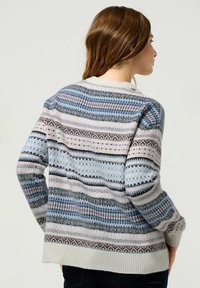 Sweter dzianinowy w jasnoniebieskim kolorze, z wzorzystymi paskami w różowym i czarnym. Okrągły dekolt oraz ściągacze przy mankietach i u dołu. Miła w dotyku faktura.