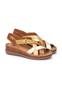 Sandalias de cuero marrón y dorado con correas entrelazadas, plantilla acolchada, costuras texturizadas y suela de goma. Correa ajustable en el tobillo para un mejor ajuste.