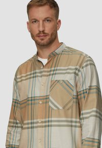 Geruite shirt in beige, witte en blauwe tinten, met een button-down kraag en zak, gemaakt van een lichte stof met een gladde textuur.