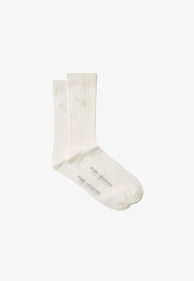 Une paire de chaussettes blanches à côtes, avec le logo PME Legend et un emblème d'aile brodé près du haut de la cheville et imprimé sur la semelle.