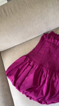 Rochie fucsia cu un corset plisat și o fustă amplă, realizată dintr-un material neted. Prezintă detalii gather la decolteu și la margine.