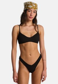 Bikini nero a coste con bralette a triangolo e perizoma a vita alta. Spalline sottili regolabili e finitura testurizzata. Completo con fascia per capelli decorata.