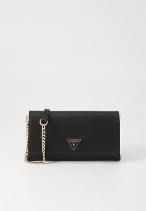 Zwarte GUESS portemonnee clutch met textuur, driehoekige logoplaat en kettinghengsel in goudkleur op een effen witte achtergrond.