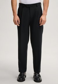 Pantalons noirs ajustés à coupe droite, dotés d'une fermeture à bouton et de poches latérales, fabriqués dans un tissu léger et lisse.