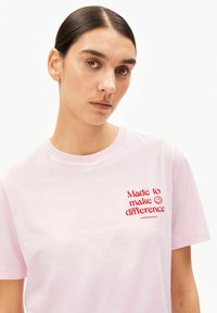 Rosa Baumwoll-T-Shirt mit Rundhalsausschnitt und rotem, besticktem Text: „Made to make a difference“. Einfaches, lässiges Design.