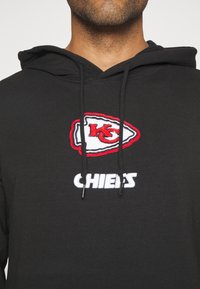 Hoodie noir en mélange de coton, avec un logo brodé rouge et blanc des Kansas City Chiefs et un texte blanc indiquant "CHIEFS."