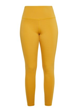 Kollased retuusid, mis on valmistatud venivast materjalist, kõrge vöökoha ja sileda tekstuuriga, sobiva disainiga, mis kitseneb pahkluude juures.