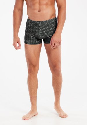 Black patterned swim trunks with a fitted design, featuring a diagonal texture and a mid-thigh length, suitable for athletic wear.