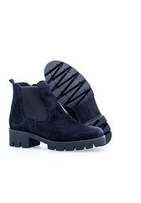 Navy suede ankle boots with elastic side panels, chunky rubber sole with tread pattern, and rounded toe design.
