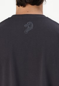 Dark gray t-shirt with short sleeves, featuring subtle octopus tentacle embroidery in a lighter gray on the back near the neckline.