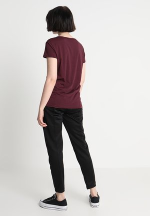 Burgundy short-sleeve t-shirt, black tapered pants, and black sneakers. Simple design with a smooth texture and no visible patterns or accents.