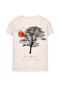 Světle růžové tričko s černou grafikou stromu, červeným sluncem a létajícími ptáky, s textem "UNIKNI A OBJEVUJ SVĚT" pod ním.