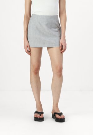 Gray mini skirt with a textured fabric. Simplistic design, straight fit, and a mid-rise waist. Paired with black flip-flop sandals.
