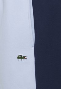 Sweat-shirt pour homme avec un design bicolore bleu et marine. Matière en mélange de coton doux, avec un petit logo crocodile vert brodé sur la poitrine.