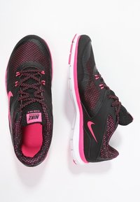 Scarpe da ginnastica nere con accenti rosa e design in rete. Presentano una suola bianca, una superficie testurizzata e un logo Nike prominente sul lato.