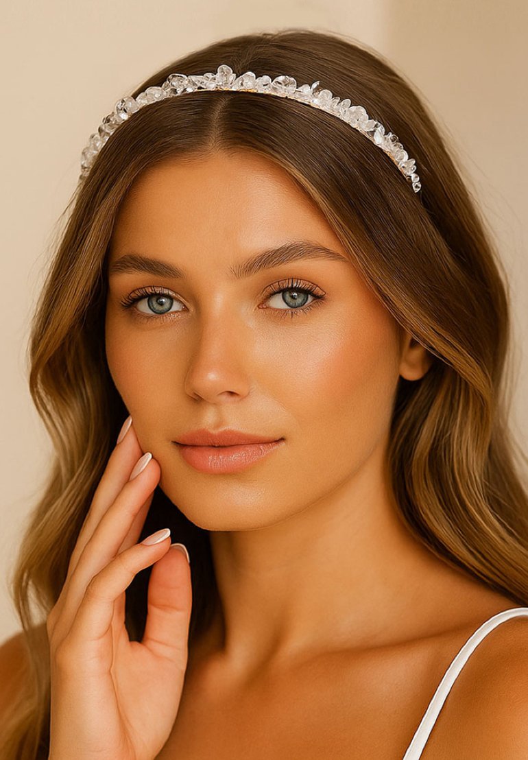 Serre-tête en cristal orné de pierres transparentes, au design délicat et à la texture lisse, porté par une personne aux cheveux longs et ondulés.