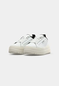 Białe skórzane trampki z czarnymi akcentami, charakteryzujące się prostym wzornictwem, grubą platformą i okrągłym noskiem. Sznurowadła zapewniają pewne dopasowanie.