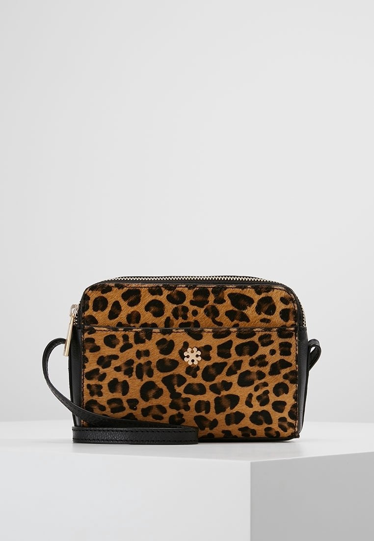 Crossbody-taske med leopardprint i brune og sorte nuancer, med sort læderrem, lynlåslukning og detaljer med guldfarvet logo.