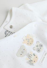 Biele mäkké detské body z látky so sivými bodkami a vyšívanými zvieracími tvárami v pastelových farbách; obsahuje cvočky na ramene.