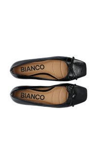 Schwarze Lackballerinas mit quadratischer Spitze, ausgestattet mit einer Schleifenakzent und einer beigen Innensohle mit der Aufschrift "BIANCO." Glatte Textur, minimalistisches Design.