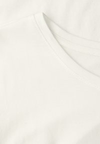 Hvid bomulds-T-shirt med rund halsudskæring, glat tekstur og flade sømme. Stoffet virker blødt og let, velegnet til afslappet brug.