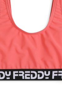 Reggiseno sportivo color corallo con scollo a U, texture liscia e una banda elastica nera con la scritta "FREDDY" in bianco.