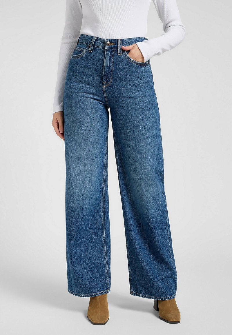 Jeans blu a vita alta e gamba larga realizzati in denim, dotati di passanti per cintura, tasche frontali e chiusura con bottone. Il tessuto presenta una consistenza sottile.