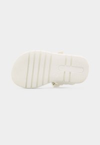 Λευκή σόλα σανδάλιου με υφασμένα οριζόντια κράτημα και ορθογώνιο άνοιγμα πάνω σε απλό λευκό φόντο.