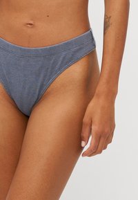 Bikini z wysokim stanem w miękkiej, teksturowanej niebieskiej tkaninie. Posiada szeroki pas, gładkie krawędzie i klasyczny krój.