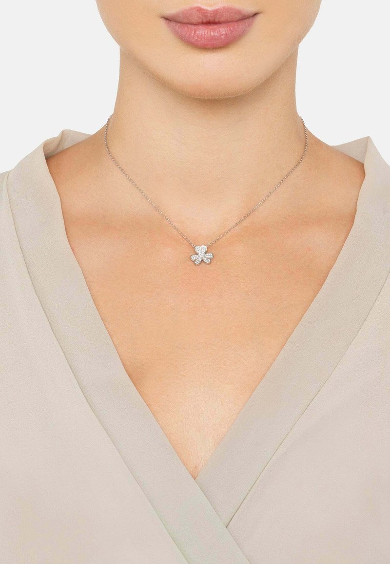 Hopeasormus, jossa on nelilehtinen apila-riipus, joka on koristeltu kirkkailla jalokivillä. Ketju on herkkä, ja riipus on kiillotettu.