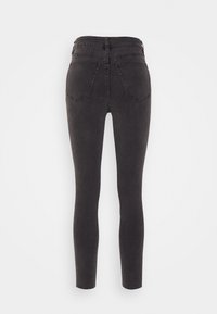 Jeans skinny em denim cinza escuro, com uma cintura alta, dois bolsos nas costas e uma textura suave. Sem ferragens ou adornos visíveis.