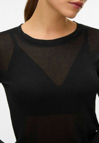Czarny sweter dziany o przezroczystej strukturze i geometrycznych wycięciach. Posiada okrągły dekolt i długie rękawy. Miękka tkanina o subtelnym połysku.