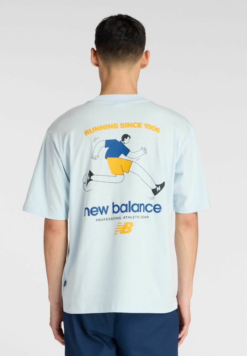 Camiseta de algodón color azul claro con un gráfico de carrera y el logo de "New Balance" en la parte trasera. Manga corta y corte relajado.