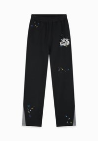 Zwarte sportbroek met een elastische tailleband, voorzien van een wit logo en gekleurde verfspatten accentueringen. Glad stof, rechte pijp ontwerp.