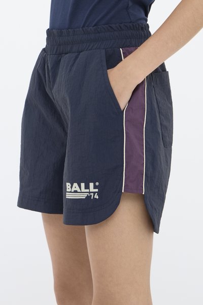 Mørkeblå shorts med teksturert stoff, elastisk midjebånd, sidelommer og en lilla panel med hvitt piping. Har hvit logo tekst.