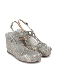 Sandalias de cuña plateadas con suela de yute trenzado, con una parte superior metálica y un detalle de cadena con joyas en la tira entre los dedos.
