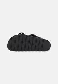 Sandal nero con suola in gomma testurizzata dotata di scanalature per una migliore aderenza, cinturini regolabili e materiale superiore liscio. Taglia 37.