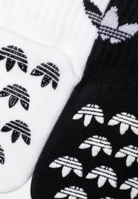 Čierne a biele bavlnené ponožky s opakujúcimi sa grafickými vzormi stylizovaných mušlí a horizontálnymi pruhmi.