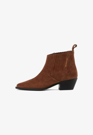 Botín de ante marrón hasta el tobillo con punta afilada, paneles laterales texturizados y tacón bajo cuadrado. Presenta una pequeña lengüeta en la parte trasera.