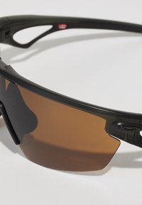 Schwarze Sportsonnenbrille mit einem geschwungenen, umschließenden Design und braunen Gläsern. Merkmale sind glänzende schwarze Akzente und leichtes Material.