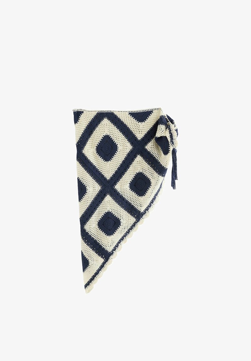 Châle triangulaire crocheté en crème et bleu marine avec des motifs en losange et un détail de pompon noué sur un côté.