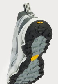 Adidași gri și albaștri cu un talpă texturată, branduirea Vibram, un tab de prindere cu un model și un design elegant și modern.