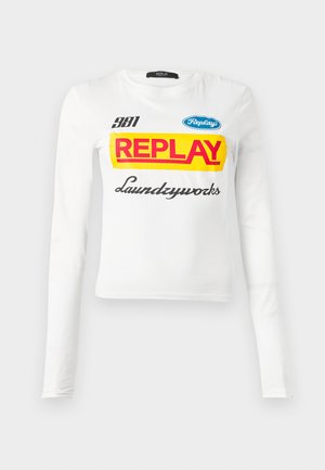Witte longsleeve shirt met vetgedrukte rode tekst "REPLAY" op een gele achtergrond, kleinere "381", blauw "Replay" logo en cursieve tekst "Laundryworks".