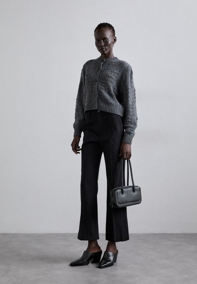 Gray knitted cardigan with textured pattern, black high-waisted trousers, black heeled mules, and a small black handbag.