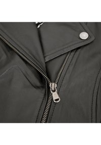 Schwarze Motorradjacke aus Leder mit einem silbernen Reißverschluss, spitzem Kragen und Druckknopfdetails. Glatte Textur mit sichtbaren Steppnähten.