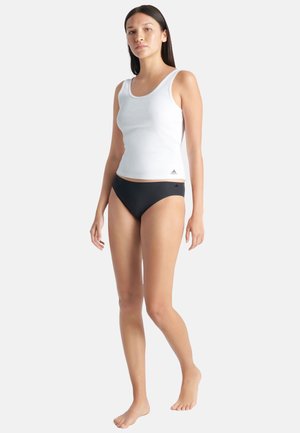 Un débardeur blanc à fines côtes et un bas de bikini noir. Le débardeur présente un col rond et est fabriqué dans un tissu extensible. Le bikini a une texture lisse.