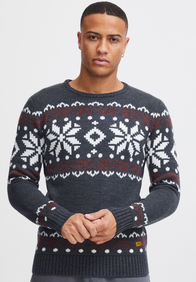 Dunkelgrauer Strickpullover mit weißen Schneeflocken- und geometrischen Mustern, akzentuiert mit kastanienbraunen Farbflächen. Rippbündchen an den Ärmeln und am Saum, runder Halsausschnitt.