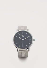 Ρολόι χειρός Calvin Klein με μαύρο καντράν, ασημένιους δείκτες ώρας, ασημένιο πλεκτό λουράκι και τρία δείκτες που δείχνουν 10:09:29.